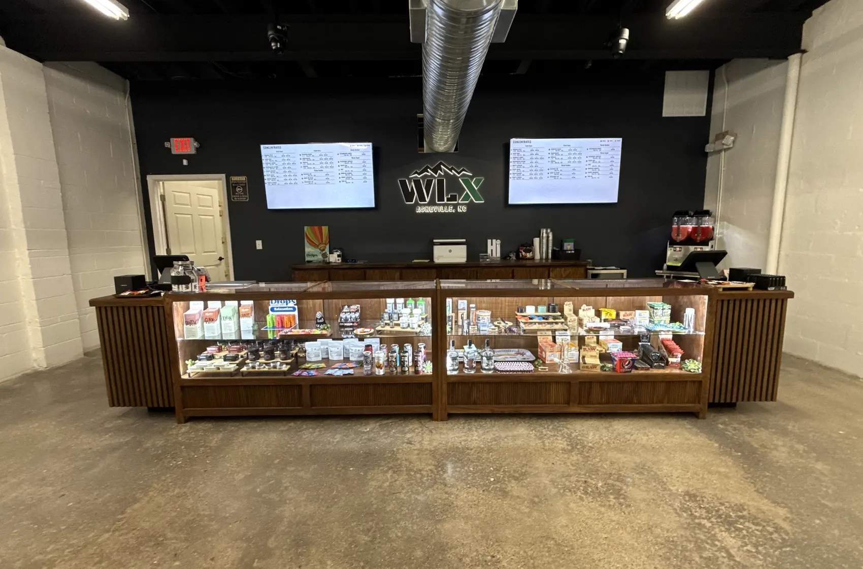 The service counter at White Label Exotics: a long walnut case with menu screens either side of the shop’s sign.