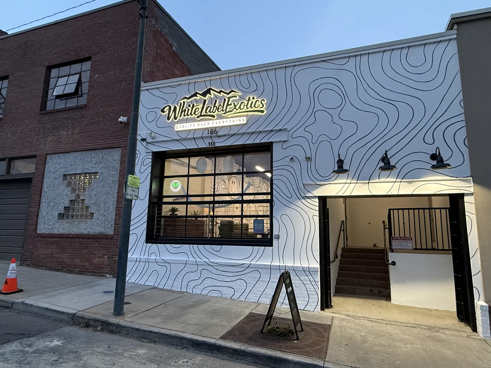 The front of White Label Exotics at dusk, its sign lit above the door.